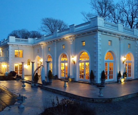 “Crawford Court” Fashioned after the Stanford White Rosecliff Mansion, this dramatic home offers grand living on a manageable scale. Iron gates open to reveal nearly one acre of inviting grounds with expansive stone terraces and a stunning pool with spa, while the home’s arch-headed doorways, columns, and balustraded roofline pay homage to its Bellevue Avenue inspiration